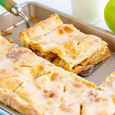 some food that is sitting in a pan on a table next to two green apples