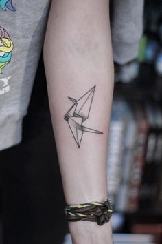 a person with a tattoo on their arm holding a knife and paper airplane in one hand