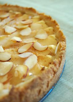 there is a pie with almonds on it sitting on a tableclothed surface