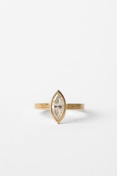 a gold ring with a pear shaped diamond in the center on a white background,