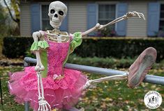 a skeleton in a pink dress is holding onto a fence