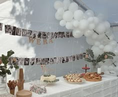 a table topped with cake and desserts under a tented area filled with balloons