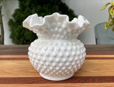 a white vase sitting on top of a wooden table