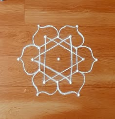 a drawing on the floor with white string and thread in it, which is shaped like a flower