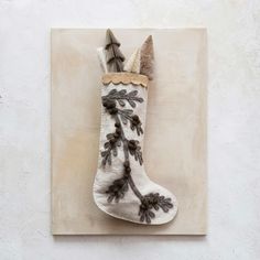 a white christmas stocking with pine cones hanging from it's side on a wall