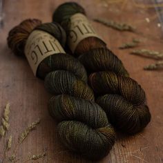 three skeins of yarn sitting on top of a wooden table next to needles