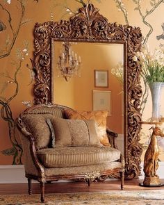 a living room with a couch, mirror and vase on the floor in front of it