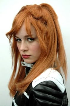 a woman with long red hair wearing a black and white outfit is looking at the camera