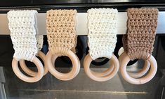 four crocheted wooden rings hanging from a hook in front of an oven door