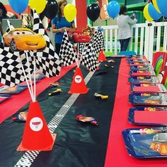 cars themed birthday party with balloons and race track tablecloths on red, black, and blue tables