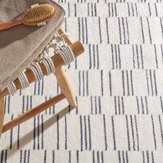 a wooden stool with a brush on top of it in front of a white and blue rug