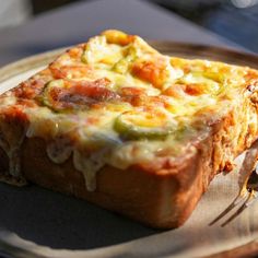 a piece of bread with cheese and vegetables on it sitting on a plate next to a fork