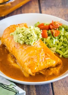 an enchilada and salad on a white plate