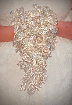 a close up of a bride's wedding dress with brooch on her arm