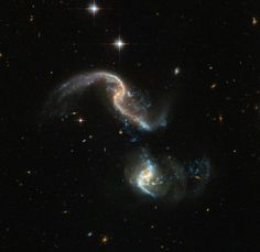 two spirally shaped objects in the middle of a dark sky with stars around them