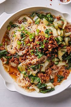 a white bowl filled with noodles, meat and vegetables