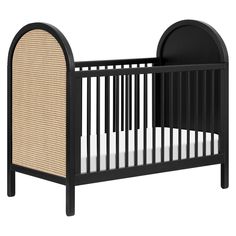 a black crib with white sheets and wicker trim on the sides, in front of a white background