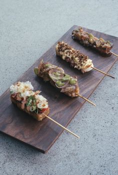 four skewered food items on a wooden board