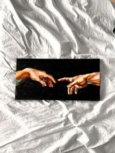 two hands touching each other on a white sheet