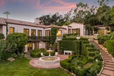 this is an image of a house with landscaping and trees in the front yard at sunset