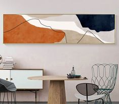 an abstract painting hangs on the wall above a dining room table with chairs and a sideboard