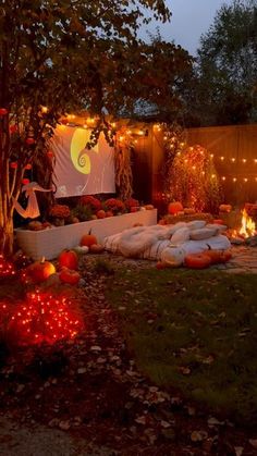 a backyard with pumpkins and lights on the ground in front of a movie screen