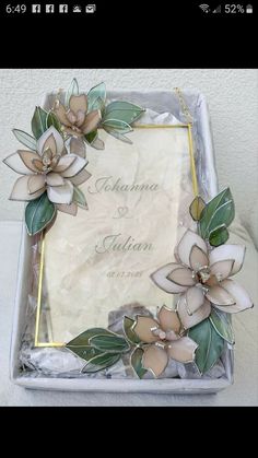 a wedding card box with flowers and leaves on the front, in gold trimming