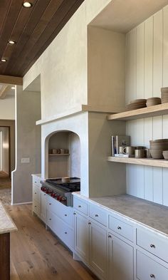 a kitchen with white cabinets and an oven in the center, along with wooden flooring