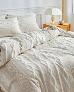 an unmade bed with white comforter and pillows on top of it in a bedroom