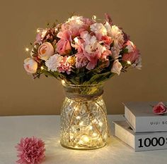 a vase filled with pink flowers sitting on top of a table next to two books