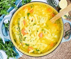 a bowl filled with chicken noodle soup on top of a blue and white cloth