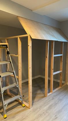 an unfinished room with ladders and shelves in it