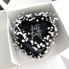 a heart shaped cake in a box with white flowers on it that says date happy