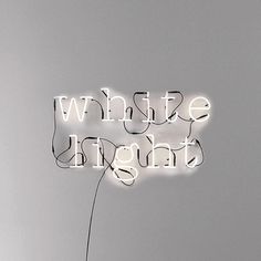 a white light sign on the side of a wall next to a vase with a plant in it