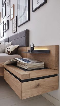 a bed sitting next to a nightstand with books on it and pictures above the headboard