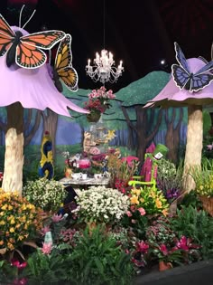 a display with lots of flowers and butterflies on the ceiling, in front of a backdrop