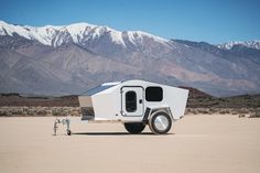 a white trailer parked in the middle of a desert with mountains in the back ground