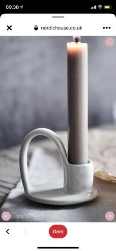 a white candle sitting on top of a table next to a cup and saucer