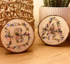 two embroidered coasters sitting on top of a table next to a potted plant