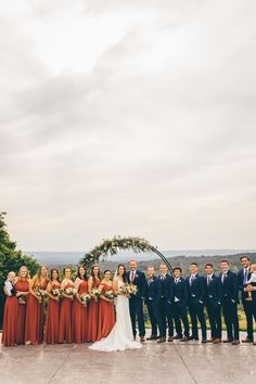 a group of people standing next to each other on top of a cement floor under a cloudy sky