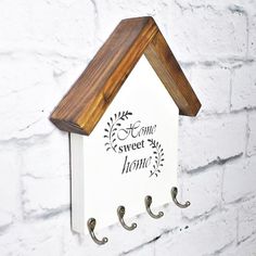 a white house shaped sign hanging on a brick wall with coat hooks and a wooden hanger