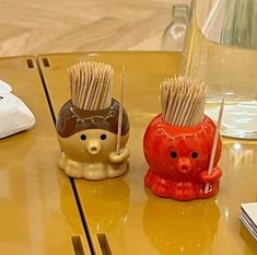 two ceramic toothbrush holders sitting on top of a table next to a glass vase