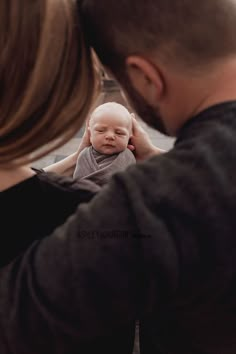 a man holding a baby up to his face in front of a woman's face