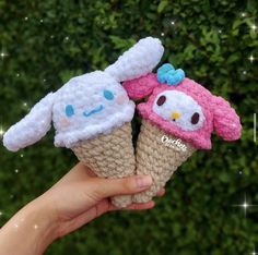 two handmade ice cream cones with hello kitty and owl faces on them are held in front of a hedge