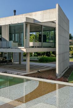 the house is made out of concrete and has glass doors on each side that lead to an outdoor pool