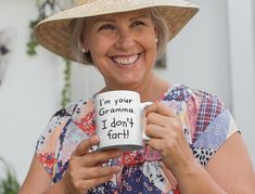 a woman wearing a straw hat holding a coffee mug that says i'm your grandma, i don't fart