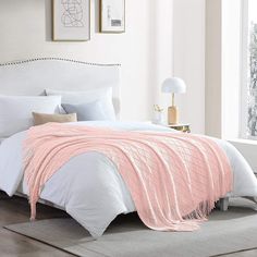 a bed with white sheets and pink blankets