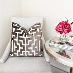 a white chair with a pillow on top of it next to a table and flowers