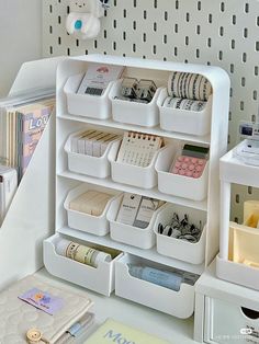 a white desk with several bins on top of it and some books in the background