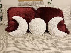 two crocheted pillows sitting on top of a bed next to a red pillow